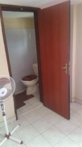 baño con aseo y puerta de madera en #1 princess self catering apartments, 230mt to senegambia business strip., en Kololi