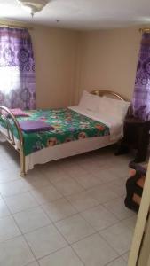 Cama pequeña en habitación con cortinas moradas en #1 princess self catering apartments, 230mt to senegambia business strip., en Kololi