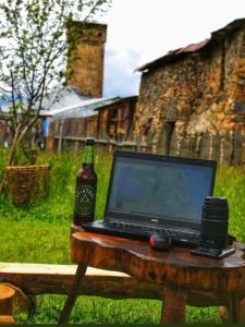 un computer portatile appoggiato su un tavolo con una bottiglia di birra di Iamze's Guest House a Mestia