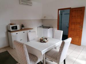 cocina con mesa blanca con sillas y microondas en Családi apartman en Tapolca