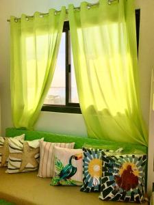 un sofá verde con almohadas frente a una ventana en 4F Bohemian Apartment for 4 with Beach View en Bangcusay