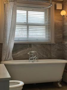 uma banheira branca na casa de banho com uma janela em Monthly & Weekly Stays - Central London Links - Business - Relocators - Contractors em Norwood