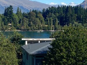 a small green building next to a river with trees at Moon House in Queenstown