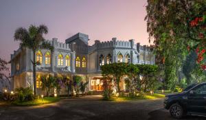 a large mansion with a car parked in front of it at Fort Munnar in Chinnakanal