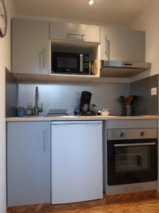 a kitchen with white cabinets and a microwave at CHALET la VEILLA in Ax-les-Thermes