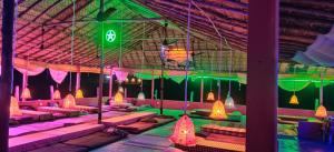 uma sala com luzes rosa e verde e bancos em Laughing Buddha hampi guest House em New Hampi