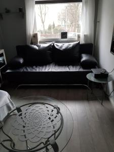 a living room with a black couch and a glass table at Apartament Mirror in Gdańsk