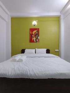 a bedroom with a white bed with a green wall at Ganga Putra Inn in Varanasi