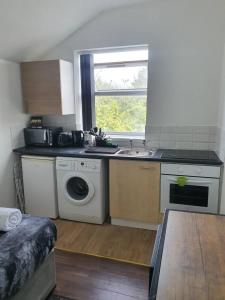 a kitchen with a sink and a washing machine at Tudors eSuites Budget Studio Apartment in Birmingham