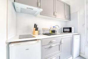 a white kitchen with white cabinets and a microwave at Magnifique Appart Cosy Rénové Gare 2 pers in Gagny