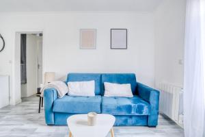 Sofá azul en la sala de estar con mesa en Magnifique Appart Cosy Rénové Gare 2 pers, en Gagny