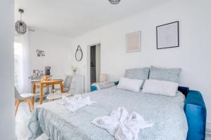 a white bedroom with a blue bed and a table at Magnifique Appart Cosy Rénové Gare 2 pers in Gagny