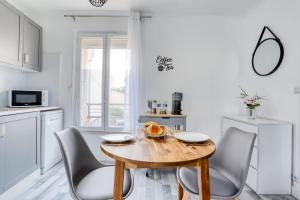 cocina y comedor con mesa de madera y sillas en Magnifique Appart Cosy Rénové Gare 2 pers, en Gagny