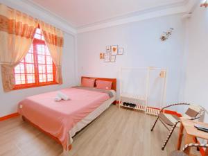 een slaapkamer met een bed, een bureau en een raam bij Happy House Homestay in Hue