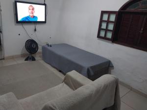 Habitación con cama y TV en la pared. en Guarus house plaza shopping, en Campos dos Goytacazes
