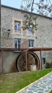 un edificio con una plataforma de madera en frente de un edificio en Le moulin de la Goutelle, en Neufmanil