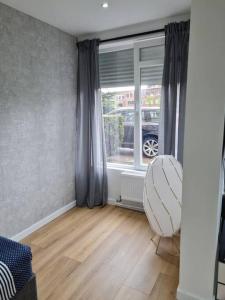 een woonkamer met een raam en een witte stoel bij ANTWERP Charming Studio in Antwerpen