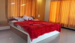a bedroom with a bed with a red blanket at Red Villa Hotel in Sasan Gir