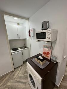 uma pequena cozinha com uma máquina de lavar roupa e um micro-ondas em SaltilloLoft em Torremolinos