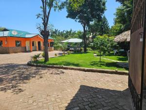 a brick courtyard with an orange building and a yard at B-MORE COMFORT STAY in Boma la Ngombe