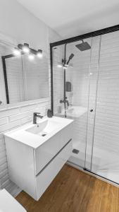 een witte badkamer met een wastafel en een douche bij Pedra Nova - Céntrico, Lujoso in Pontevedra