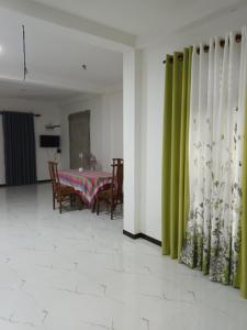 une salle à manger avec une table et des rideaux verts dans l'établissement White's villa, à Matara