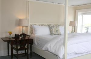 a bedroom with a white bed and a table with a chair at Anchorage 1770 in Beaufort