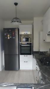 een keuken met een zwarte koelkast en een magnetron bij Location chambre dans une charmante et grande maison duplex neuve et bien aérée in La Verrière