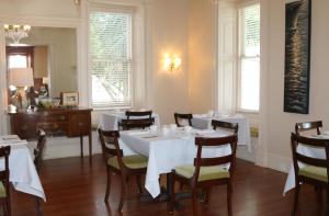 una sala da pranzo con tavoli e sedie bianchi e finestre di Anchorage 1770 a Beaufort