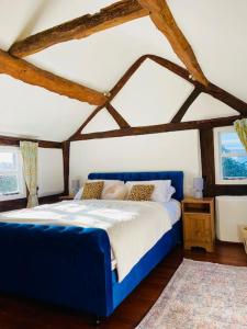 um quarto com uma cama azul e 2 janelas em Log Burner and Beamed Ceilings-2 Bed Cottage Crumpelbury and Whitbourne Hall less than a 4 minute drive Dog walking trails and local pub within walking distance and a 30 minute drive to the Malvern Hills em Worcester
