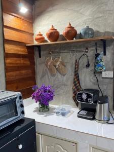 a kitchen with a counter with a microwave and flowers at Cozycomo Chiang Dao - Pha Mok in Amphoe Chiang Dao