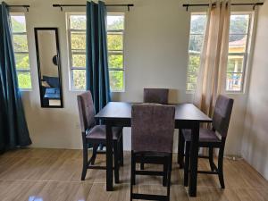 Royal Escape - 2 في Anse La Raye: طاولة طعام وكراسي في غرفة بها نوافذ