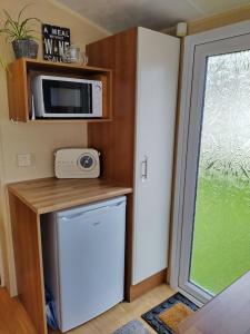 a small kitchen with a microwave and a refrigerator at Carnival Our lovely home from home in Great Yarmouth