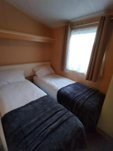 twee bedden in een kleine kamer met een raam bij Carnival Our lovely home from home in Great Yarmouth
