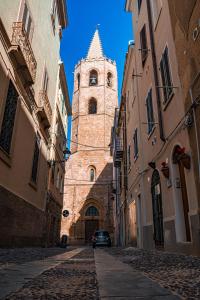 un edificio con una torre de reloj en medio de una calle en Casa del Campanil en Alghero