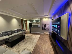 a living room with a couch and a large flat screen tv at أجنحة لافينا الخاصة in Yanbu
