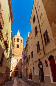 un callejón entre dos edificios con una torre de reloj en Casa del Campanil, en Alghero