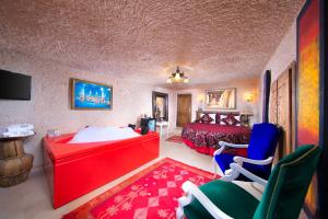 a bedroom with a bed and a red desk and chairs at Cappadocia Fairy Chimneys Selfie Cave Hotels - Balloon View Experience in Uçhisar