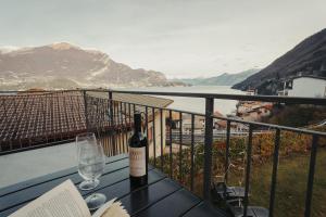 レッツェノにあるVillaGrassi - Charming Villa by Lake Comoのワイングラス付きのテーブルに座ったワイン1本