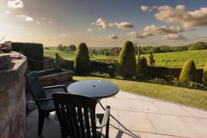 a patio with a table and chairs and a field at The Old Workshop in Higher Burwardsley
