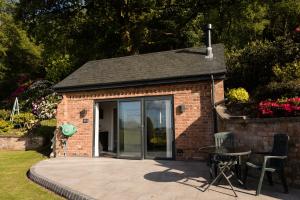 a small brick building with a patio and a table at The Old Workshop in Higher Burwardsley