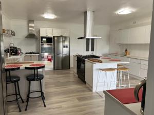 una cocina con armarios blancos y una isla con taburetes. en Longhorn Ranch Apartments, en Orbost