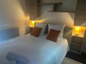 1 dormitorio con 1 cama blanca con 2 almohadas y 2 lámparas en La mansarde de la Lône, en La Roche-de-Glun