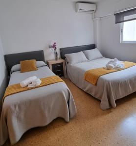 two beds sitting next to each other in a room at Pension Colón in San Juan de Alicante
