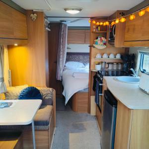 a small room with a kitchen and a bed at Kintyre Caravan in Portree