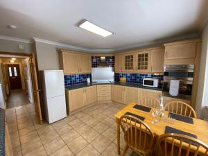 uma cozinha com uma mesa e um frigorífico branco em Lyngarrie em Dufftown