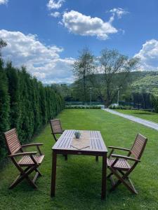 three chairs and a wooden picnic table in a field at Apartman Azul in Podastrana