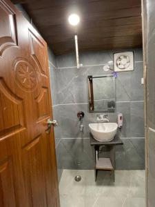 a bathroom with a sink and a wooden door at Landour Exotica in Mussoorie