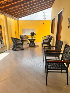 eine Terrasse mit Stühlen, einem Tisch und einer gelben Wand in der Unterkunft Casa de Praia Maceió in Maceió