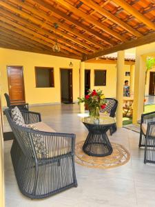 eine Terrasse mit Stühlen und einem Tisch mit einer Blumenvase in der Unterkunft Casa de Praia Maceió in Maceió